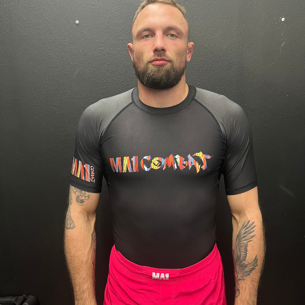 MA1 CHAOTIC KNIT LOGO BLACK SHORT SLEEVE RASH GUARD
